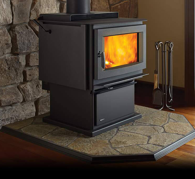 Wood stove with flames inside, placed against a stone wall.